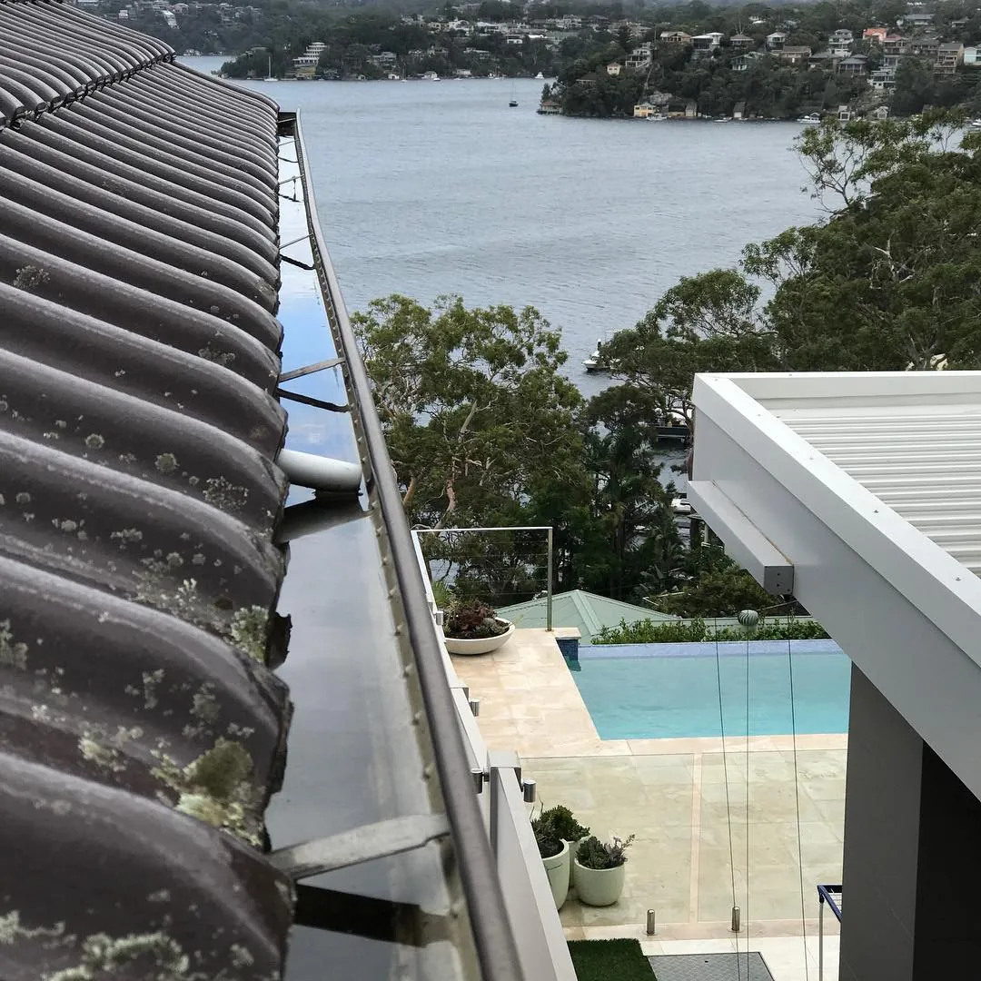 A clear gutter on a tile roof above a pool, after cleaning