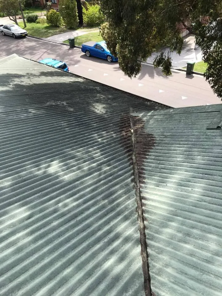 The same roof valley after cleaning, every leaf gone, the old water stain still on the metal